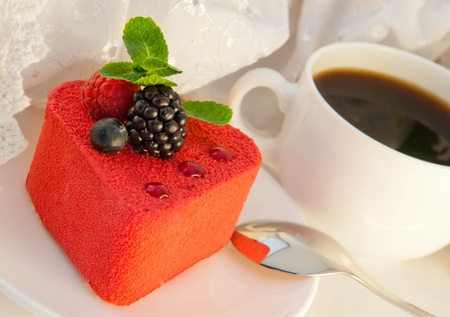 Cake in the form of heart with a blackberry, a raspberry and mint, a cup of coffeeの写真素材