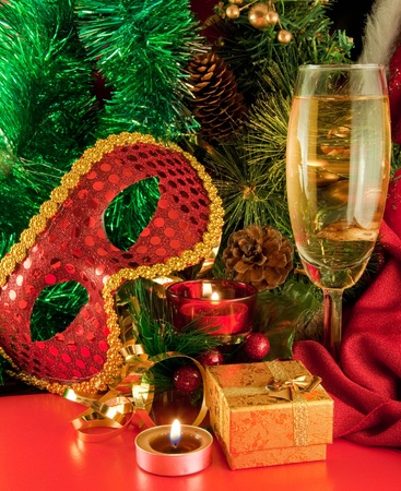 Christmas card. Champagne, a branch of a fur-tree, a candle and a carnival maskの写真素材