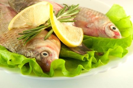 Fresh fish, crucian with a lemon and an onions, salad with olive oilの写真素材