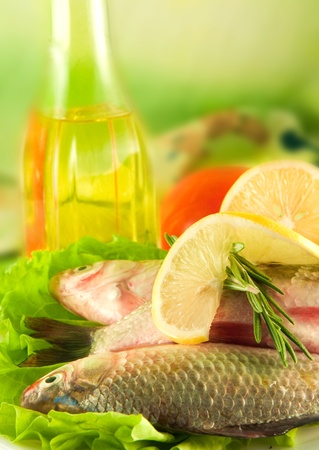 Fresh fish, crucian with a lemon and an onions, salad with olive oilの写真素材