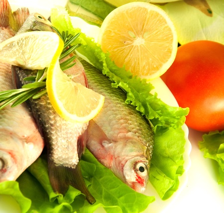 Fresh fish, crucian with a lemon and an onions, salad with olive oil