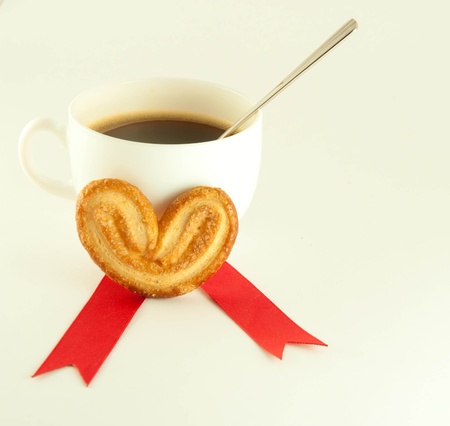 Cake in the form of heart with red ribbon , a cup of coffeeの写真素材