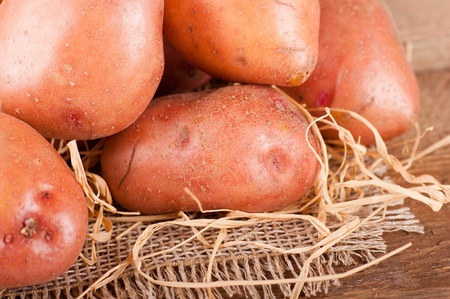 Crude potatoes on a bag, green leavesの写真素材