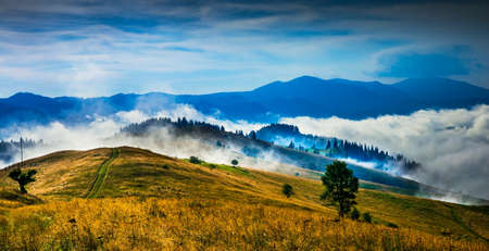 Amazing mountain landscape with fog and a haystackの写真素材