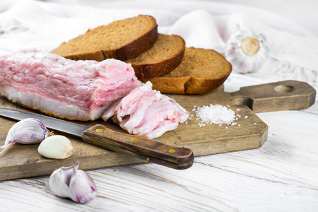 Bacon with onion and garlic on a wooden boardの写真素材