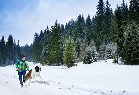 Attractive young boy and girl playing with a dog is on snow-covered field.の写真素材