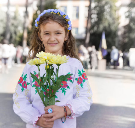 Ukrainian Schoolgirl in a wreath and embroidered shirt and with patriotic flowers against the war in Ukraineの写真素材