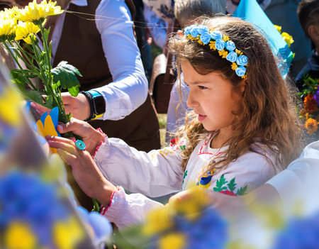 Ukrainian Schoolgirl in a wreath and embroidered shirt and with patriotic flowers against the war in Ukraineの写真素材