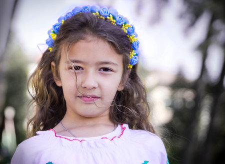 Ukrainian Schoolgirl in a wreath and embroidered shirt and with patriotic flowers against the war in...