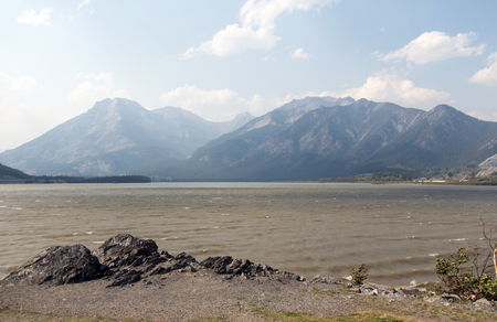 Mountains visible through the haze of forest fire smoke along the banks of the Bow River in Alberta, Canada.の写真素材