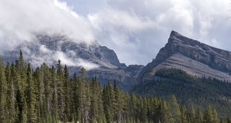 Two mountain peaks in Kananaskis country. One veiled by clouds, the other not.の写真素材
