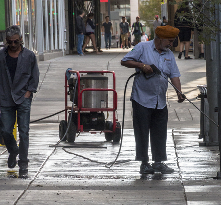 Calgary, Alberta/Canada â August 30, 2015: A man pressure-washing a sidewalk outside of a business in Calgary, Alberta.のeditorial素材