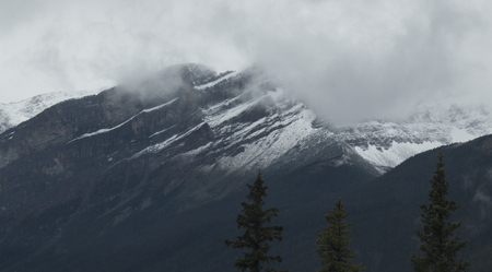 An angular mountain in the Canadian Rockies is partially obscured by clouds.の写真素材