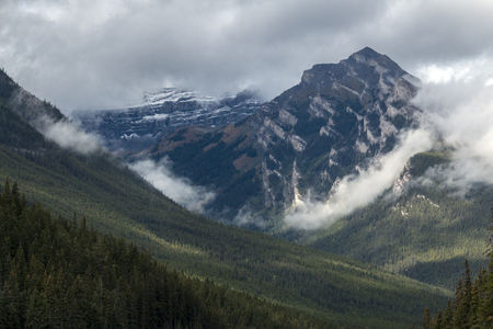 Low-flying clouds hug the contours of a mountain in Banff National Park, Alberta, Canada.の写真素材