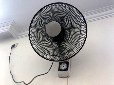 old dirty dusty fan on the wall is inserted in the socketの写真素材