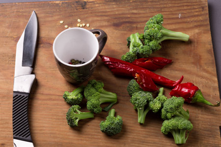 Fresh broccoli and chili pepper with pepper seeds on wooden deskの写真素材
