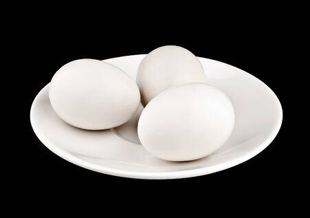 Three eggs on plate on black backgroundの写真素材