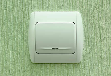 Electrical white rocker light switch on green wall