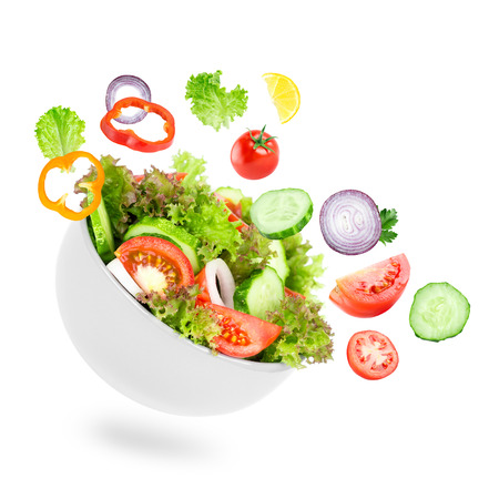 Fresh salad. Mixed falling vegetables in bowl on white backgroundの写真素材
