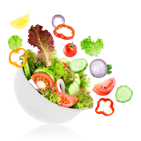 Fresh salad. Mixed falling vegetables in bowl on white backgroundの写真素材