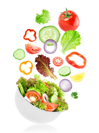 Fresh salad. Mixed falling vegetables in bowl on white backgroundの写真素材