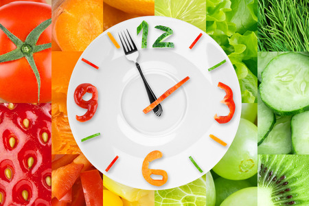 Food clock with vegetables and fruits as background. Healthy food conceptの写真素材