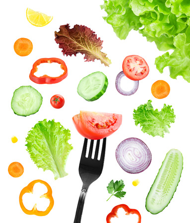 Fresh vegetables falling on fork on white background. Food conceptの写真素材