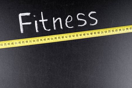 Fitness word written on a chalkboard with measuring tape. Conceptの写真素材
