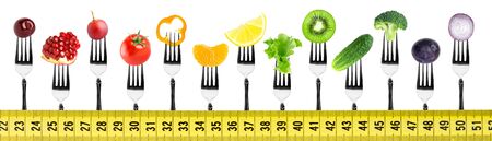 Fruits and vegetables on fork with measuring tape on white background. Food conceptの写真素材