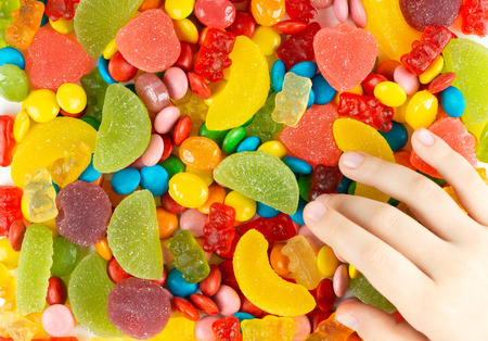 Child's hand reaches for the sweets. Candy backgroundの写真素材