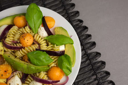 pasta salad consisting of fusili with mozzarella and melon with avocado and red onionsの写真素材