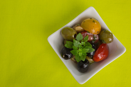 Mediterranean antipasti salad with mozzarella balls, green and black olives and cherry tomatoes and some tiny-leafed basil.の写真素材