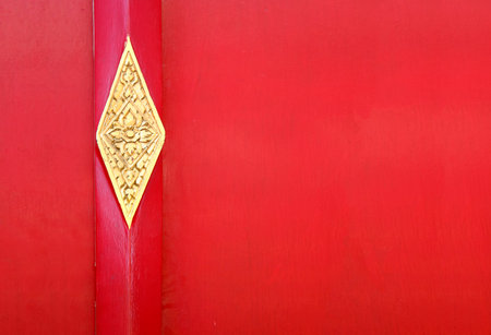 Red door with metallic element in asian style. Red wooden gate with golden details. Door with thai floral ornament.の写真素材