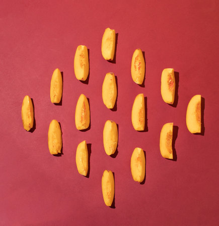 Creative pattern made with fresh peaches slice on dark red background. Minimal summer fruit arrangement.の写真素材
