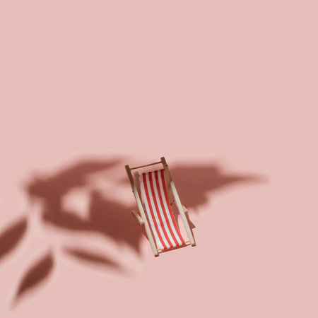 Sun lounger in the shade of leaves on a pink background. Minimal Summer concept.