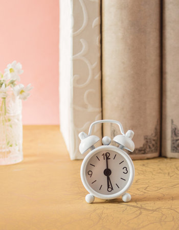 White clock and ordered books on pastel pink background. Minimal education concept. flat lay.の写真素材