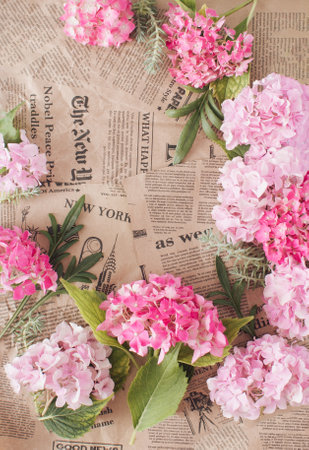 Creative arrangements of pink flowers on a newspaper background. Retro celebrating concept. Top viewの写真素材