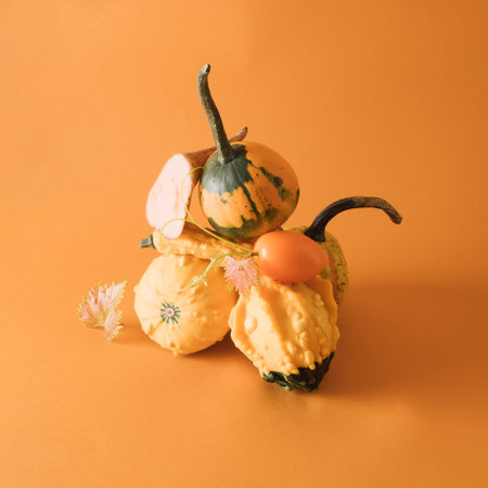 Creative balancing vertical pyramid of freshly picked home grown natural vegetables in orange and yellow color - pumpkin same color background, copy space. Vegetarian healthy food.の写真素材