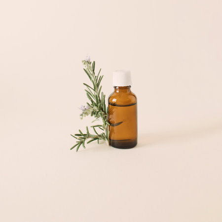 Bottle of essential oil with fresh rosemary twig on a white background. Creative concept of healthy relaxationの写真素材