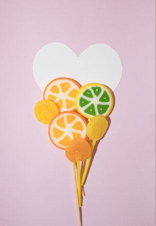 Lollipops and a heart against lilac background. Love and Valentine's Day concept. Flat layの写真素材