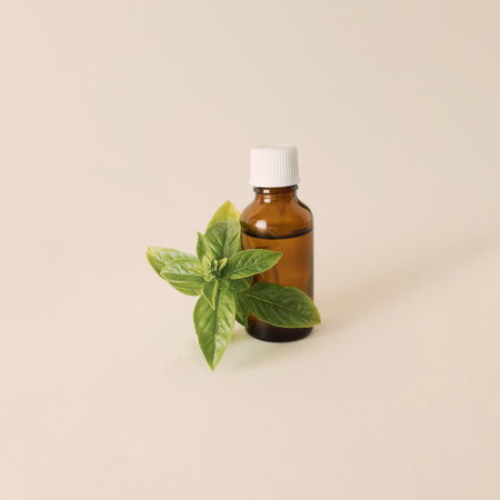 Bottle of essential oil with fresh basil twig on a white background. Creative concept of healthy relaxationの写真素材