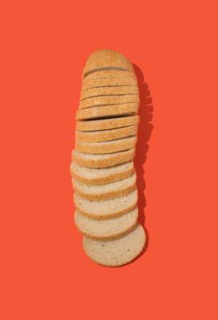 Overhead view of arranged slices of fresh white bread with sesame seeds against orange background. Bakery conceptの写真素材