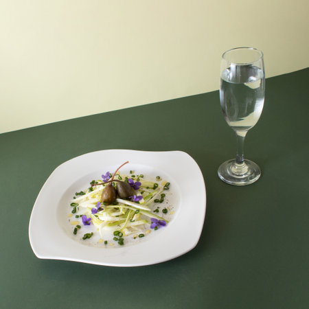 Vegan meal of zucchini, capers, spices, violets and a glass of water. Healthy food concept. Flat lay.の写真素材