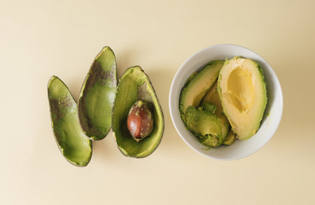Emptied shell of an avocado and half avocado with copy space on beige background. Sliced fresh...