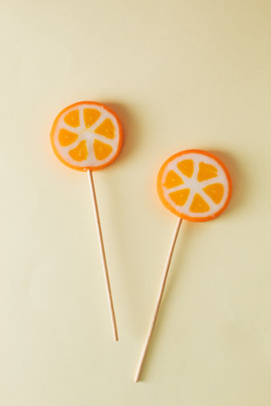 Two orange lollipops on beige background. Minimal concept ideaの写真素材