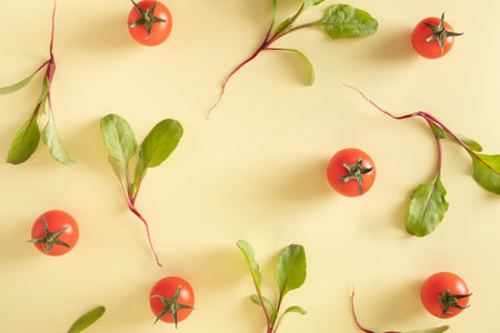 Creative arranged deconstructed salad of cherry tomatoes and baby beets arranged on a pastel yellow backgroundの写真素材