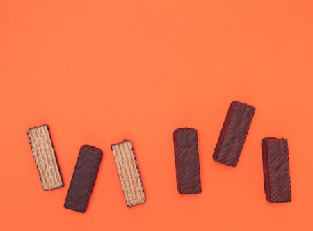 Chocolate wafers lined up on an orange background. Copy spaceの写真素材