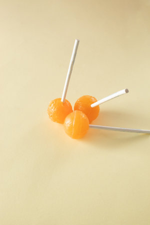 Three orange lollipops on beige background. Minimal concept ideaの写真素材