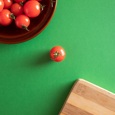 Cherry tomatoes on brown ceramic plate and kitchen board with green surface. Flat lay, copy spaceの写真素材