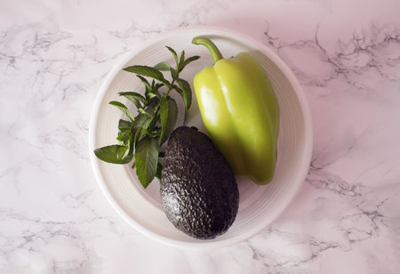 Green pepper, mentha and avocado on plastic plate on kitchen table.の写真素材